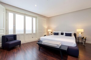 Een slaapkamer met een groot bed, bedlampen, een bankje en een stoel.