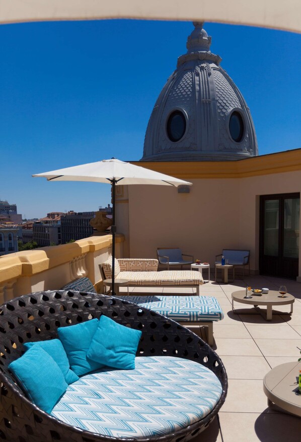 Une terrasse sur le toit, dotée d’un espace extérieur aménagé avec des sièges, d’un grand parasol et d’une structure distinctive en forme de dôme.
