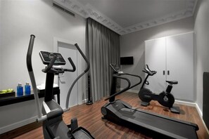 A home gym with a treadmill, elliptical, and stationary bike, a TV, and a door with a mirror. - Sardinero Madrid (Madrid)