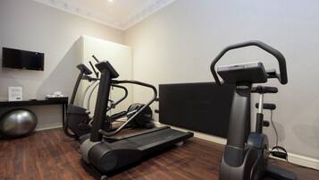 Un gimnasio en casa con dos cintas de correr, una bicicleta estática y una pelota de ejercicio grande.