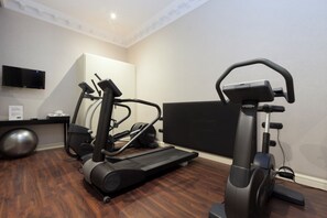 Een sportschool thuis met twee loopbanden, een hometrainer en een grote fitnessbal.