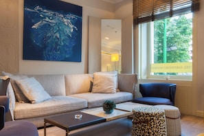 Un salon moderne avec un canapé, une table basse et un pouf à motifs.