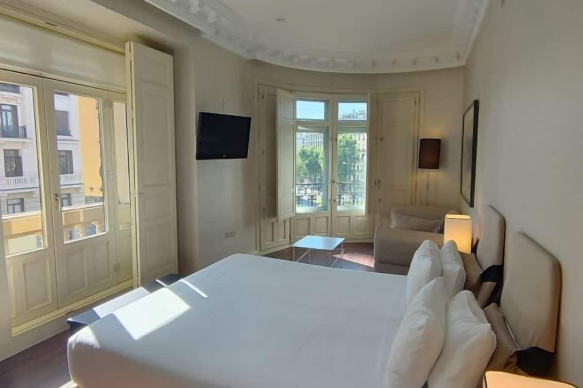 Une chambre d’hôtel avec un grand lit, une télévision, une petite table et une vue sur l’extérieur.