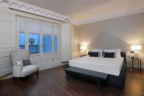 A bedroom with a large bed, a chair, a wardrobe, and two bedside lamps. - Sardinero Madrid (Madrid)