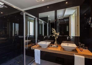 Ein modernes Badezimmer mit zwei Waschbecken, einem großen Spiegel und einer Duschkabine aus Glas.