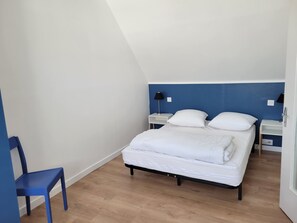 Une chambre Ă coucher avec un lit, une chaise et une table de chevet avec une lampe.