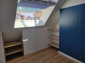 Ein Zimmer mit Dachfenster, Holzregalen und einer blauen Akzentwand.