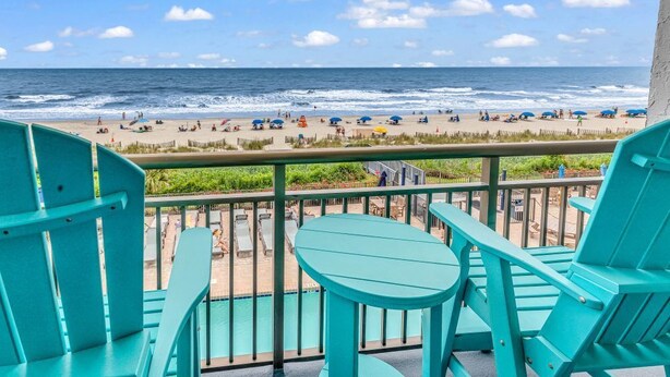 A balcony with turquoise chairs and a view of the beach.