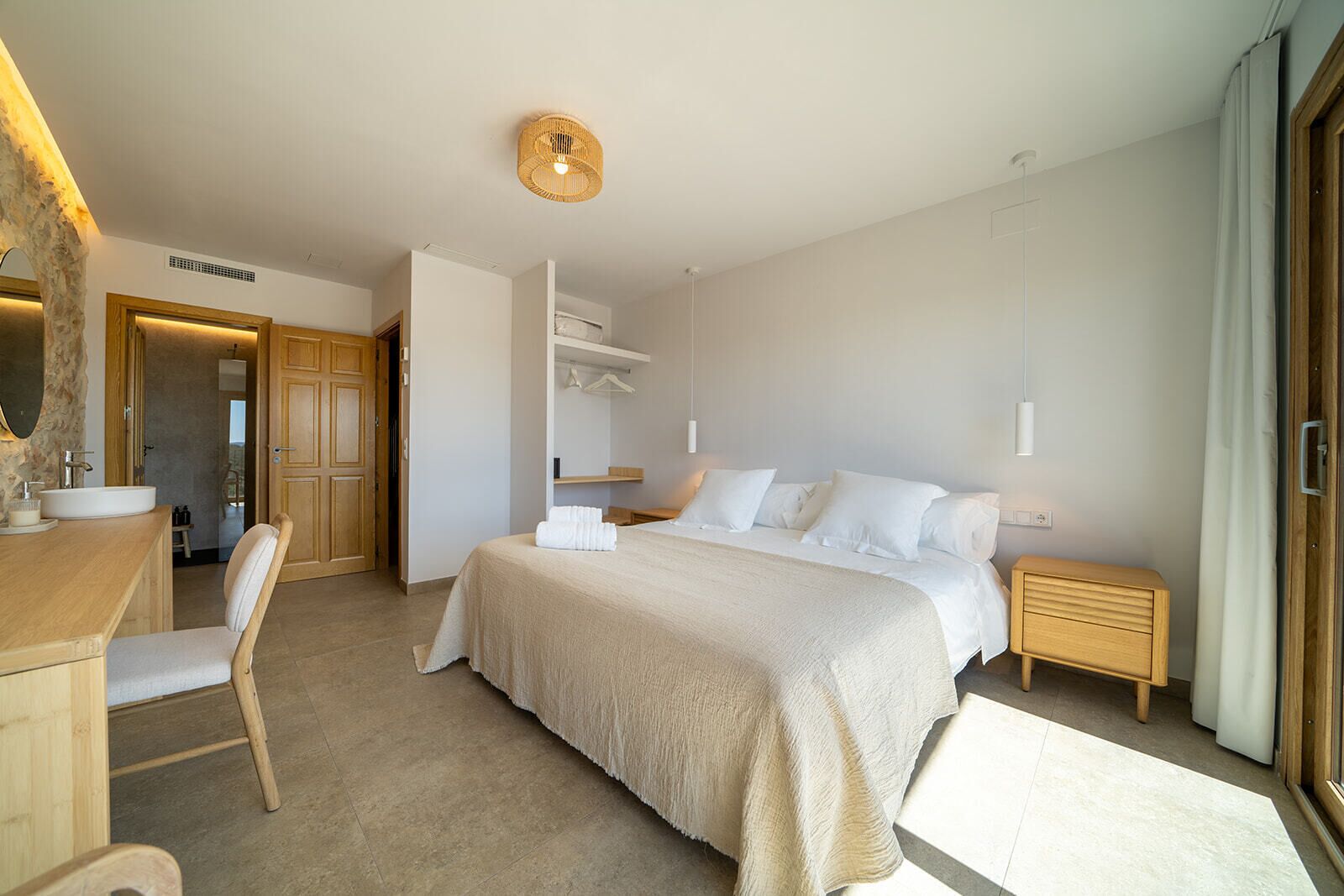 Moderni hotellihuone, jossa on suuri sänky, puinen työpöytä, tuoli, yöpöytä ja peili.