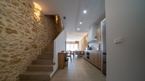 A modern kitchen with a stone wall, wooden staircase, and a dining area. - OSTALEA Boutique Rural House with Jacuzzi, near the beach and medieval villages. (Vilanova d'Alcolea)