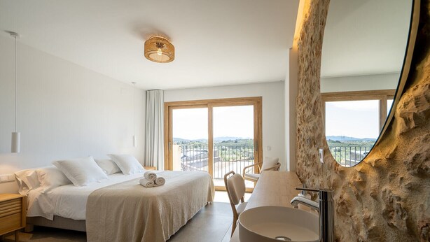 A modern hotel room with a large bed, a round sink, and a balcony with a view. - OSTALEA Boutique Rural House with Jacuzzi, near the beach and medieval villages. (Vilanova d'Alcolea)