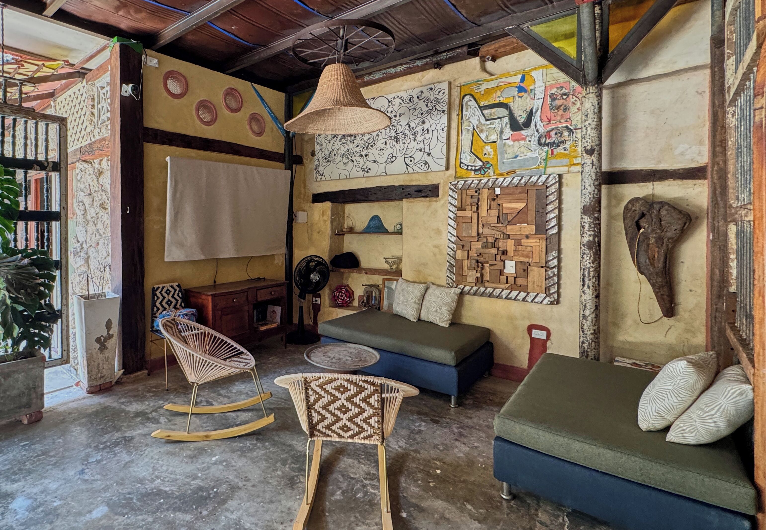 A cozy living room with a sofa, rocking chairs, and a fan.