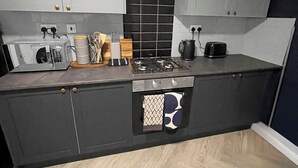 A modern kitchen with grey cabinets, a gas stove, a microwave, and a toaster.