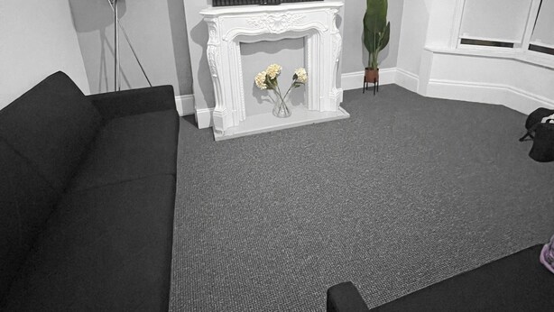 A living room with a fireplace, a television mounted above it, and a sofa.