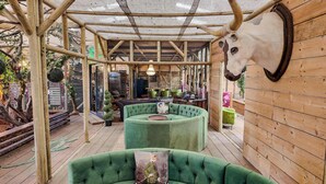 A rustic wooden interior with a green sofa and a mounted animal head. - Berney Lodge - Puppy Lounge, arcades, games room (Faldingworth)