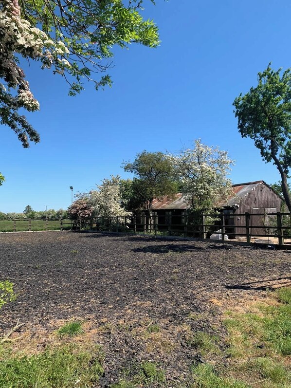 A rural landscape with a fenced area, a wooden barn, and a clear blue sky. - Berney Lodge - arcades, games room (Faldingworth)
