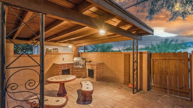 An outdoor patio with a brick barbecue, two stools, and a table. - Serene 3BR retreat with Catalina Mountain views, shaded gazebo, BBQ grill & dog-friendly backyard. (Tucson)