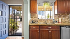 A kitchen with wooden cabinets, a granite countertop, a stainless steel dishwasher, and a window with a view of the outside. - Serene 3BR retreat with Catalina Mountain views, shaded gazebo, BBQ grill & dog-friendly backyard. (Tucson)