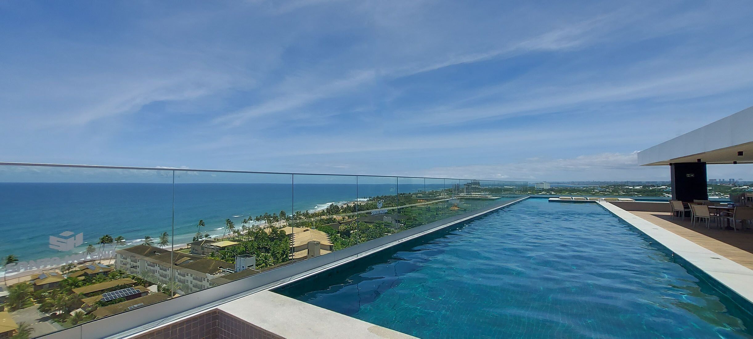 A rooftop infinity pool with a clear view of the ocean and cityscape.