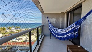 A balcony with a hammock, a view of the ocean, and tiled walls.