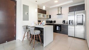 A modern kitchen with a central island, stainless steel appliances, and pendant lighting. - Luxury Penthouse 3Bdr with pool (Kingston)