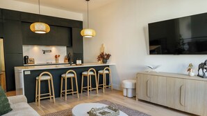 Eine moderne Küche mit dunklen Schränken, einer weißen Arbeitsplatte und einer Bar mit Barhocker.
