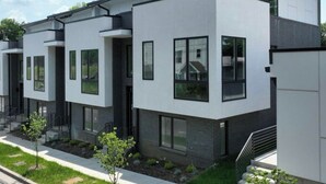 Ein modernes Wohngebäude mit zwei Etagen, flachem Dach, großen Fenstern und minimalistischem Design.
