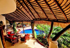 A poolside area with a thatched roof, outdoor furniture, and lush tropical plants. - Phenomenal 6-bedroom hotel in Playa Matapalo (Playa Matapalo)