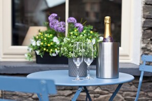 Een tafel met twee champagneglazen en een metalen champagnefles op een blauwe tafel.