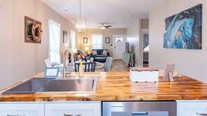 A modern kitchen with a wooden countertop, stainless steel sink, and pendant lights. - Pet Friendly! Cozy Beach Cottage Minutes to Downtown and ILM-Fenced Backyard! (Wilmington)