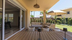 Un patio al aire libre con suelo de madera, un conjunto de sofás y una mesa con una lámpara.