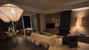 Una sala de estar moderna con una mesa de comedor de madera oscura, sofás color beige y una chimenea.