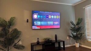 Un téléviseur à écran plat fixé au mur affiche l’interface d’une application de diffusion en continu, proposant diverses options de divertissement.