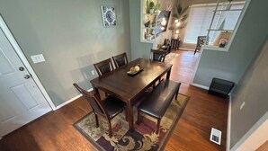 Un espace repas comprenant une table et des chaises en bois, un banc et un tapis décoratif.