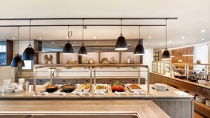 A buffet setup with multiple food stations and hanging pendant lights.