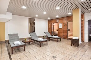 A spa area with three lounge chairs, a small table, and a wooden wall.