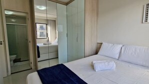 A hotel room with a bed, a bathroom with a toilet and shower, and a wardrobe. - COJMG0101 - Cond. Canto Belo Aeroporto (Salvador)