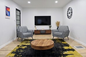 Relax in comfort with a large flat-screen TV, two plush armchairs, and a convenient coffee table.