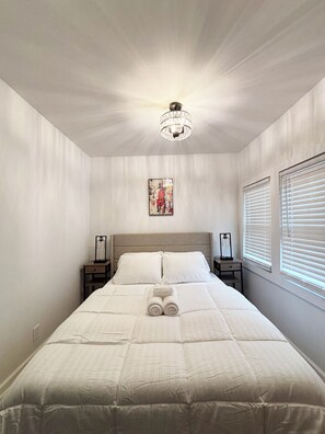 Relax in this serene bedroom with a large bed, two bedside tables, and a stylish chandelier.