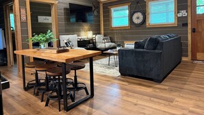 A cozy cabin interior with a dining area, a sofa, and a clock on the wall.
