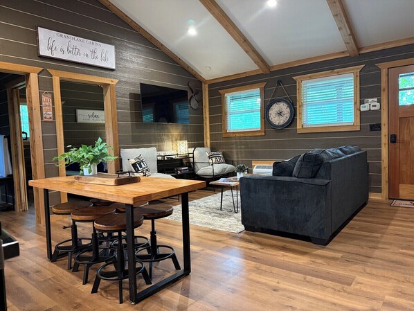 A cozy cabin interior with a dining area, a sofa, and a clock on the wall.