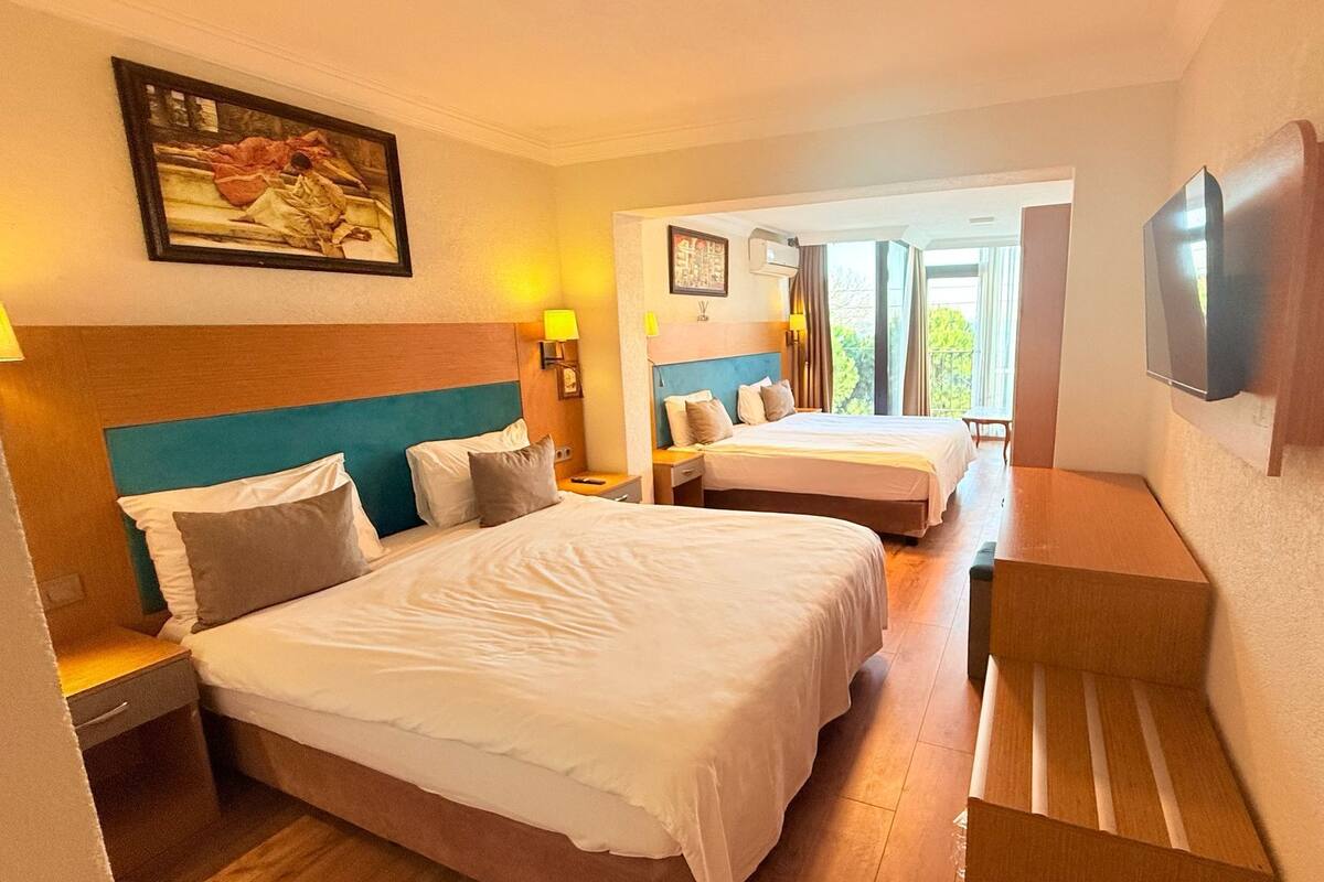 A hotel room with two beds, a TV, and a painting on the wall.