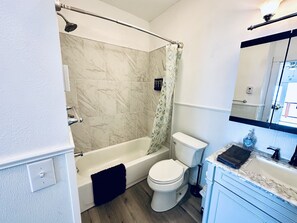 Een badkamer met een bad, toilet en wastafel.