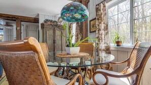 Un coin repas avec des chaises en osier, une table en verre et un luminaire suspendu en vitrail.
