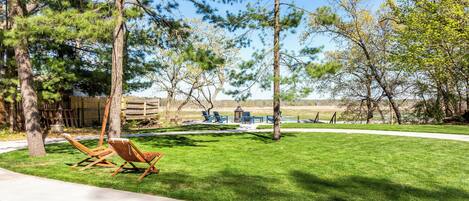 Ein Garten mit Rasen, zwei Holzstühlen und einer Holzterrasse.