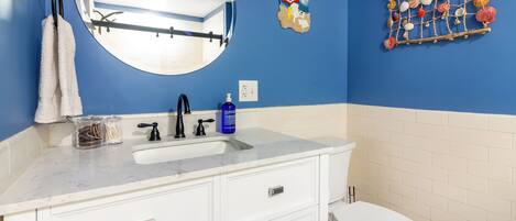 A bathroom with a blue wall, white vanity, and a white toilet.