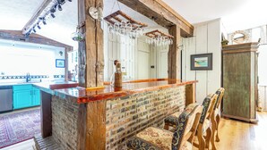 Une cuisine rustique avec un mur en briques, un comptoir de bar en bois et des verres suspendus.