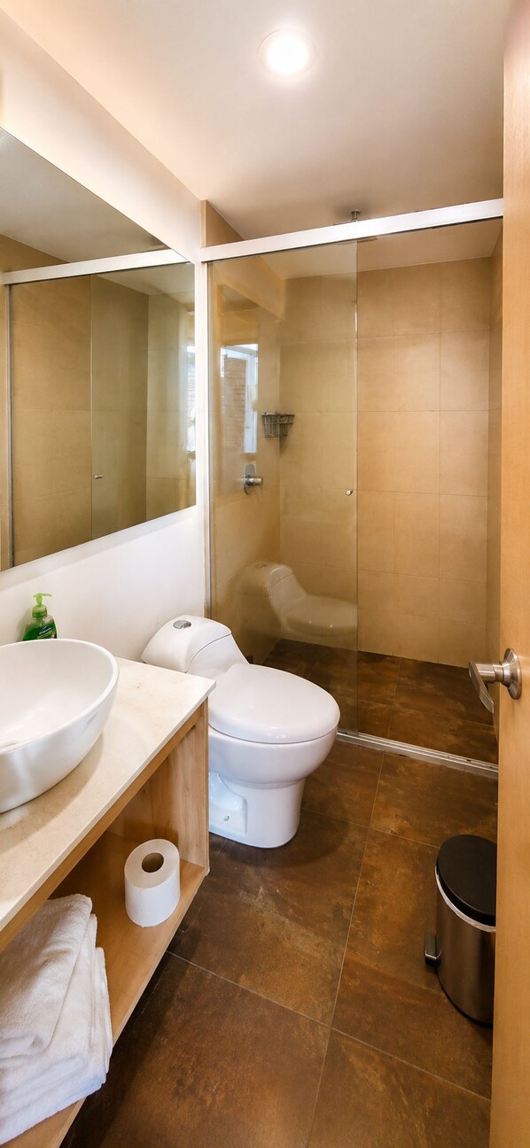 A modern bathroom with a glass-enclosed shower, a white sink, and a toilet.