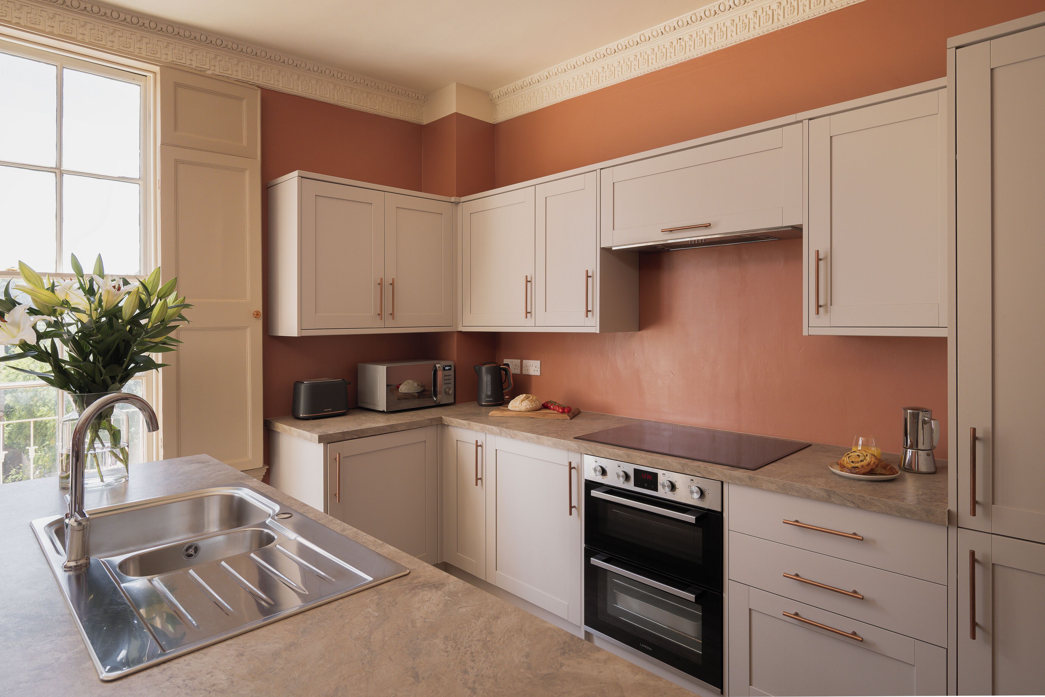 A kitchen with white cabinets, a stainless steel sink, a toaster, and an oven.