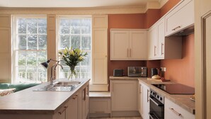 A modern kitchen with a large window, built-in appliances, and a light-colored wood floor.